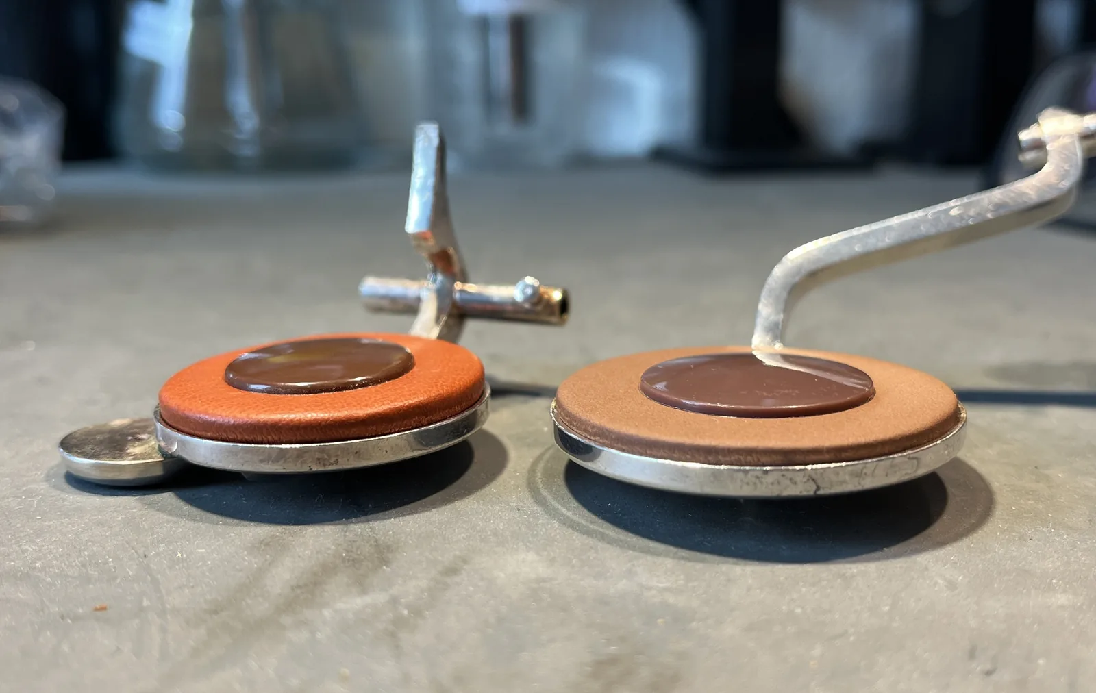 Two saxophone keys with new pads seen from the side – an orange pad and a light brown pad with a clear difference in thickness