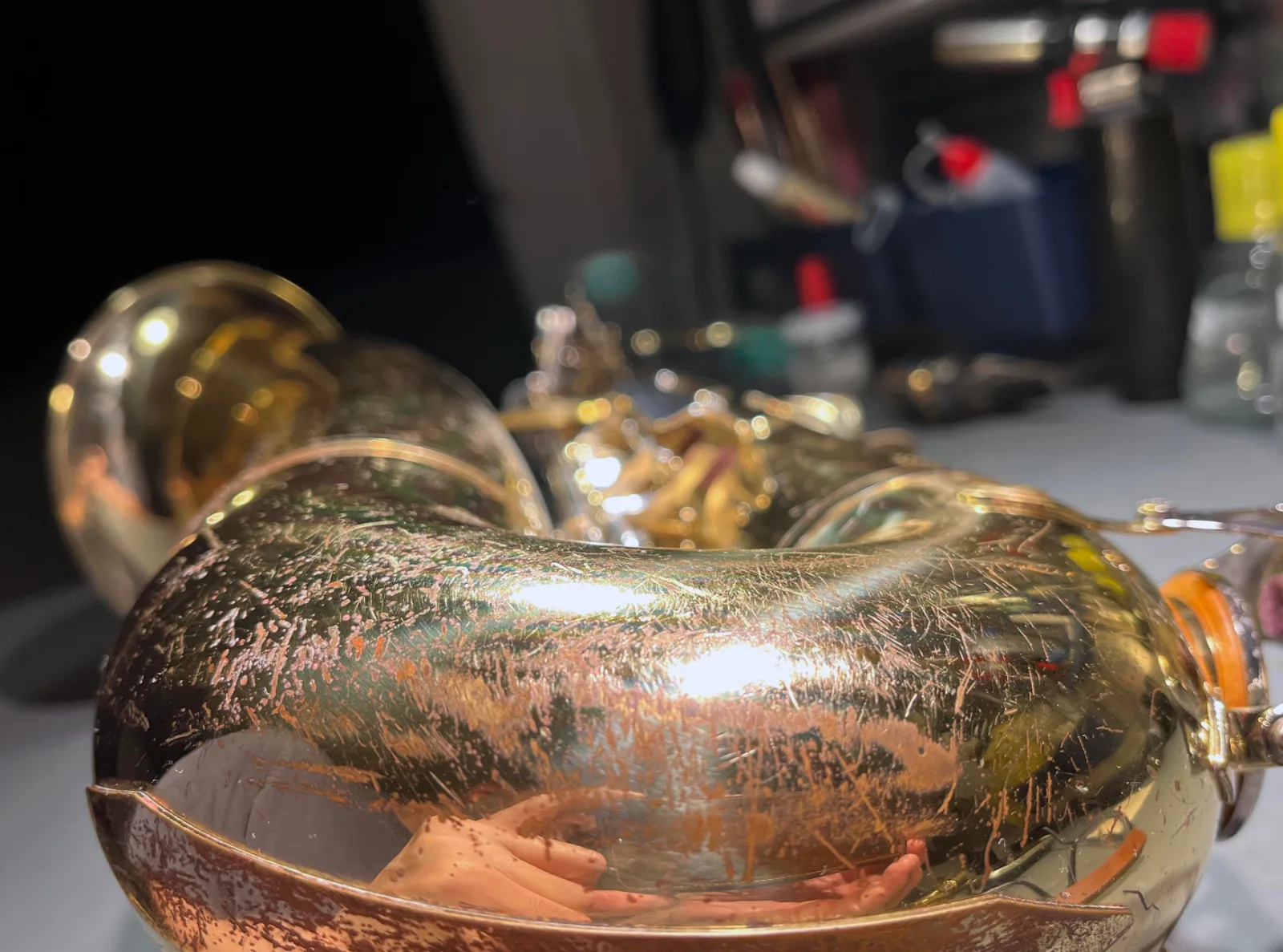 Close-up of the bow of a saxophone with heavily worn and scratched lacquer